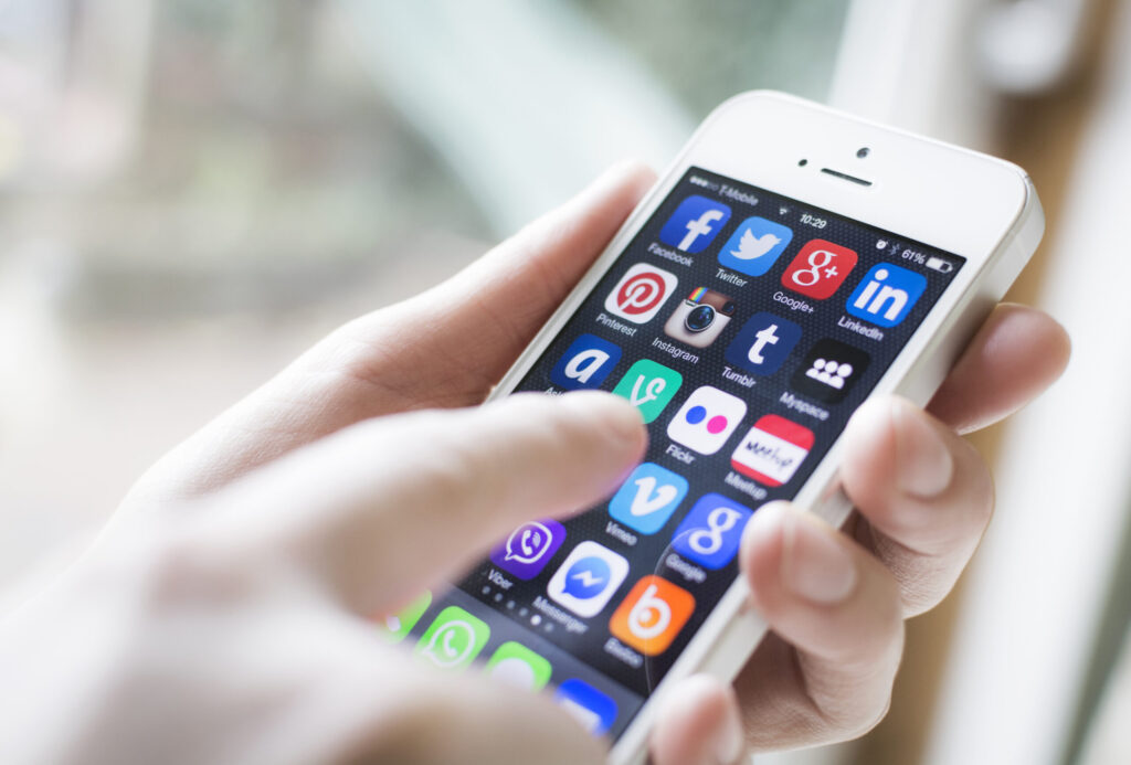 Hand holding a smart phone and finger about to touch an app icon on the home screen 